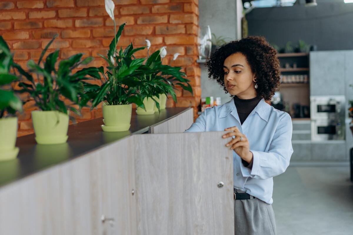 employee looking in cupboard with plants on top, green office